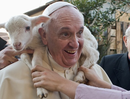 A lamb sits around the neck of Pope Francis as he visits a Nativity scene at the Church of St. Alfonso Maria dei Liguori in Rome Jan. 6. (CNS photo/L'Osservatore Romano via Reuters) (Jan. 7, 2014)