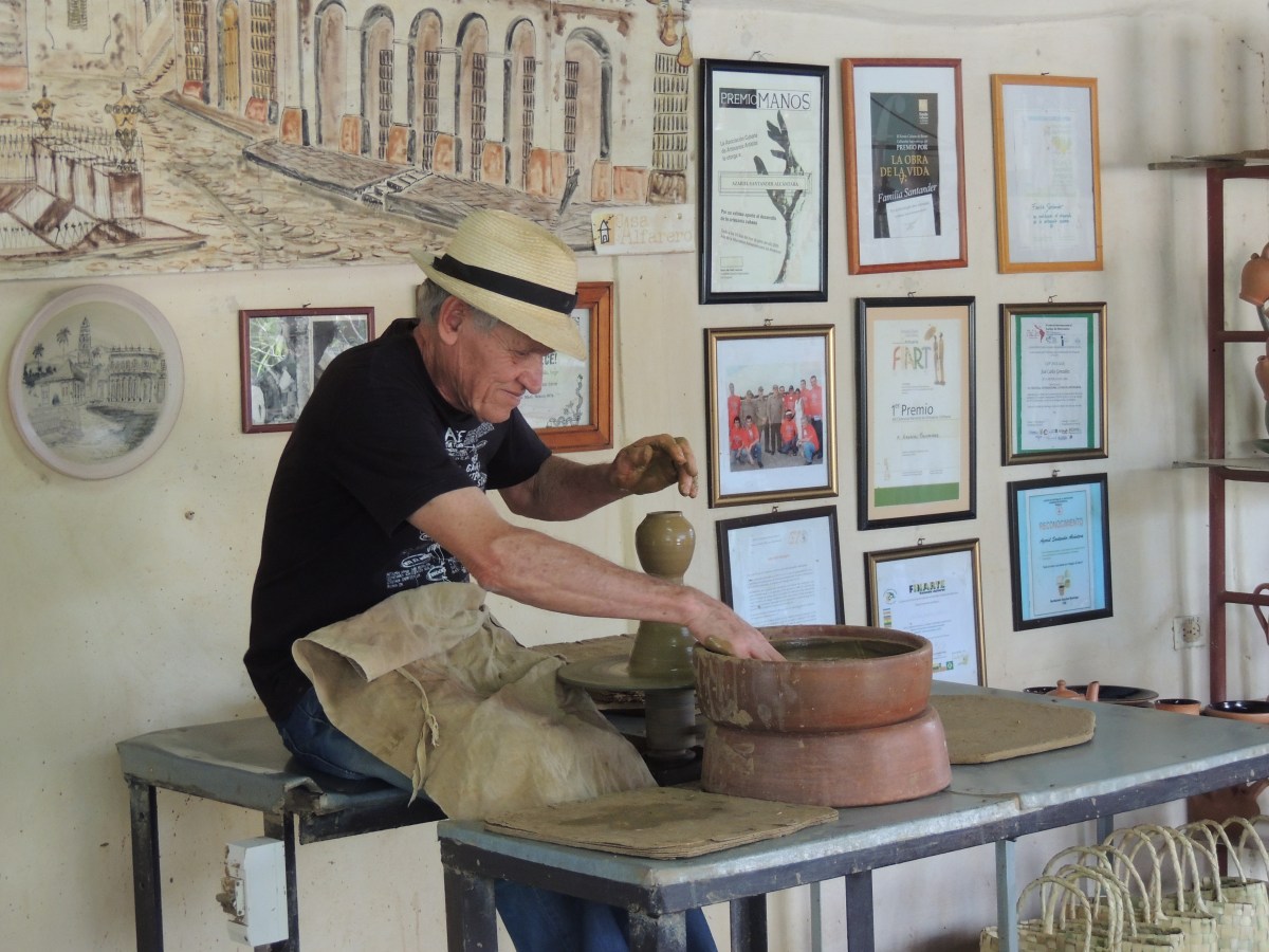 Potter at work in Trinidad. Educational tours to artists' studios create opportunities for exchange and chance to buy paintings, ceramics, sculpture and other art.