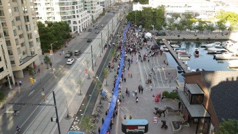 A small section of the 650 metre ribbon passing through the crowd gathered at the 650-meter Simcoe Wave Deck. Photo credit CNW
