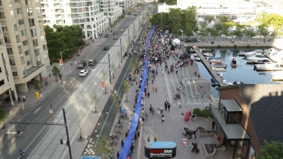 A small section of the 650 metre ribbon passing through the crowd gathered at the 650-meter Simcoe Wave Deck. Photo credit CNW